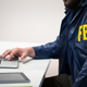 stock image of person on laptop wearing FBI jacket